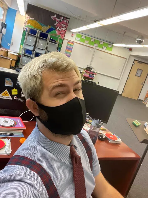 David in his classroom during the pandemic, wearing a black face mask.